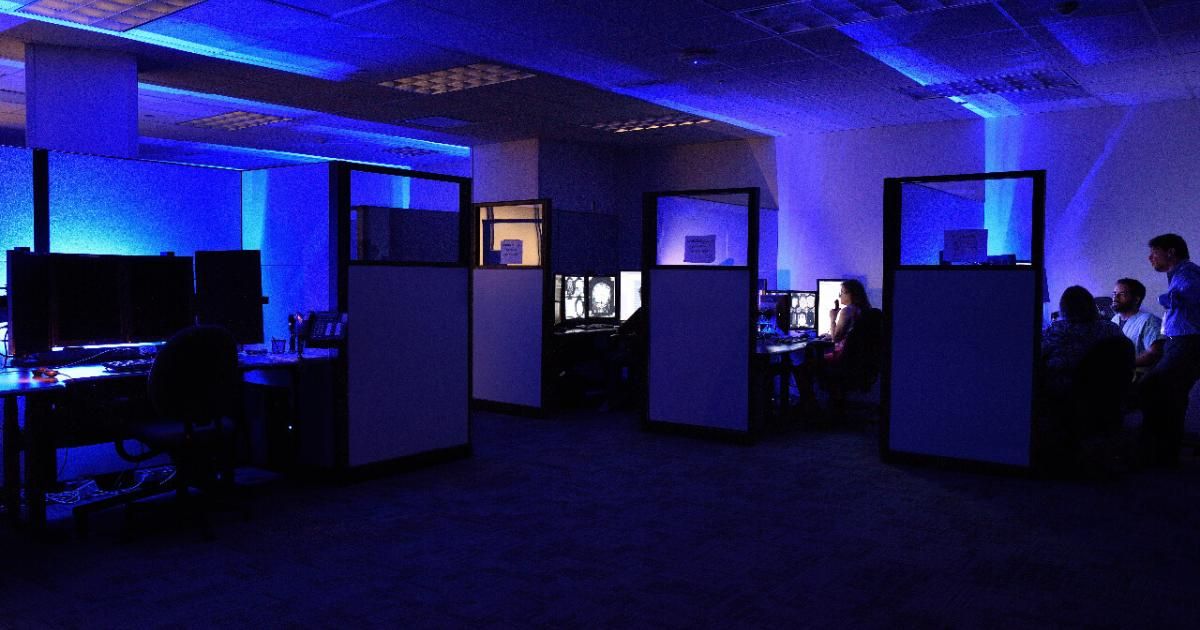 dark office cubicles with blue light from screens showing patient scans